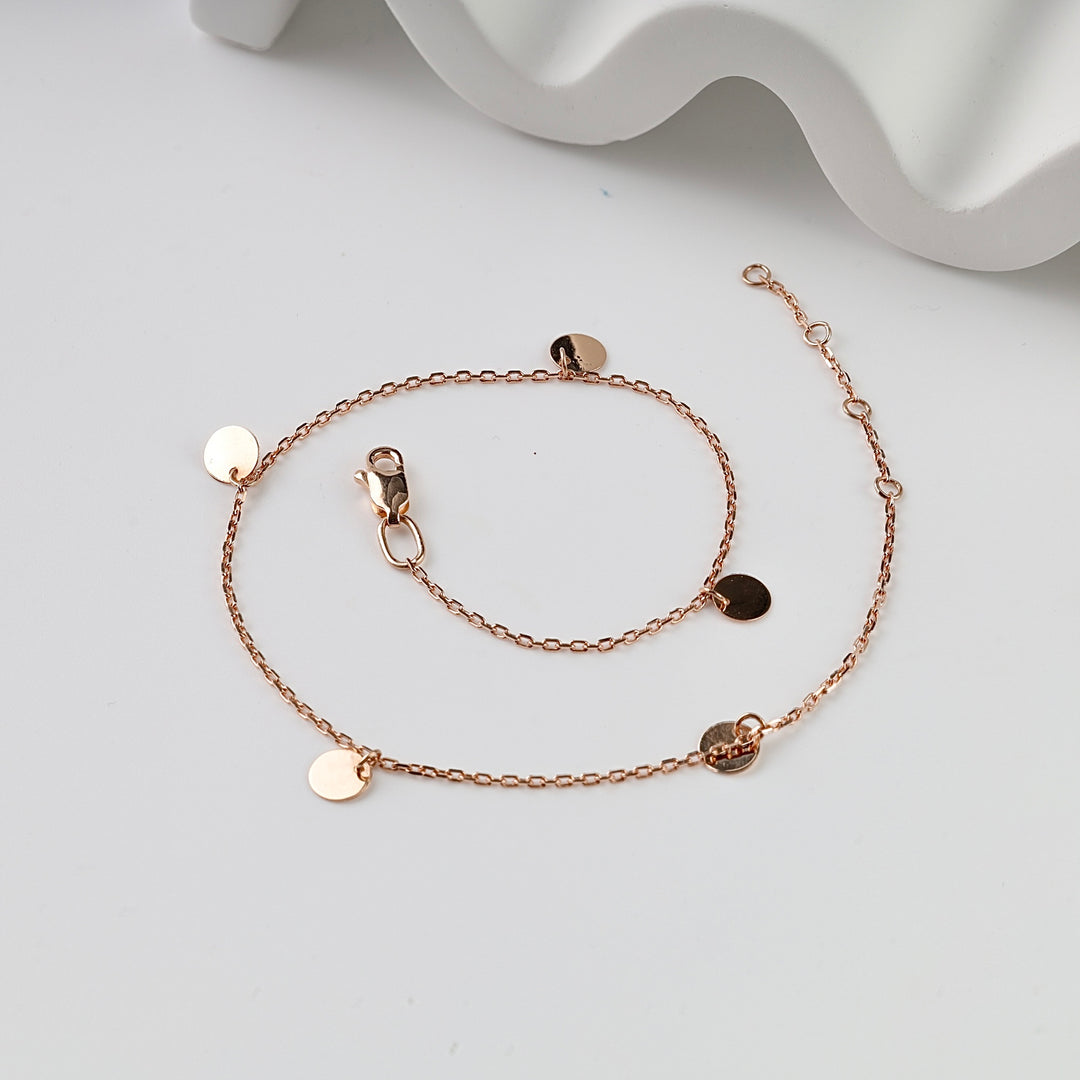 Rose gold chain bracelet with round disc charms, lobster clasp, and adjustable extender on a white background.