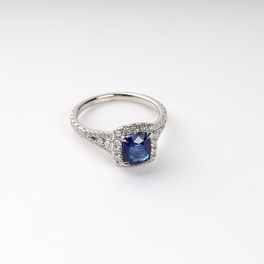Silver engagement ring with a square blue sapphire center stone and clear diamond accents on a white background.