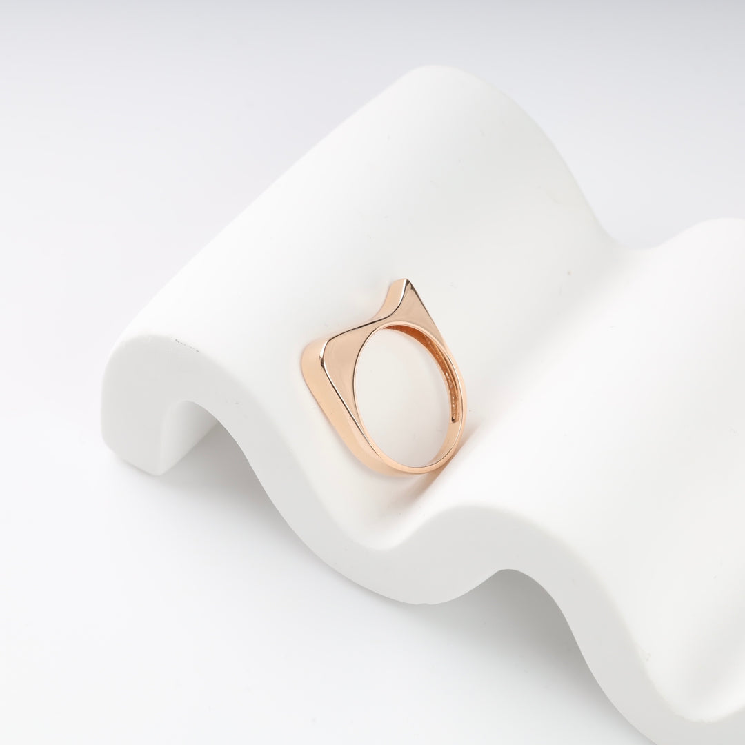 Gold geometric ring on a white wavy surface.