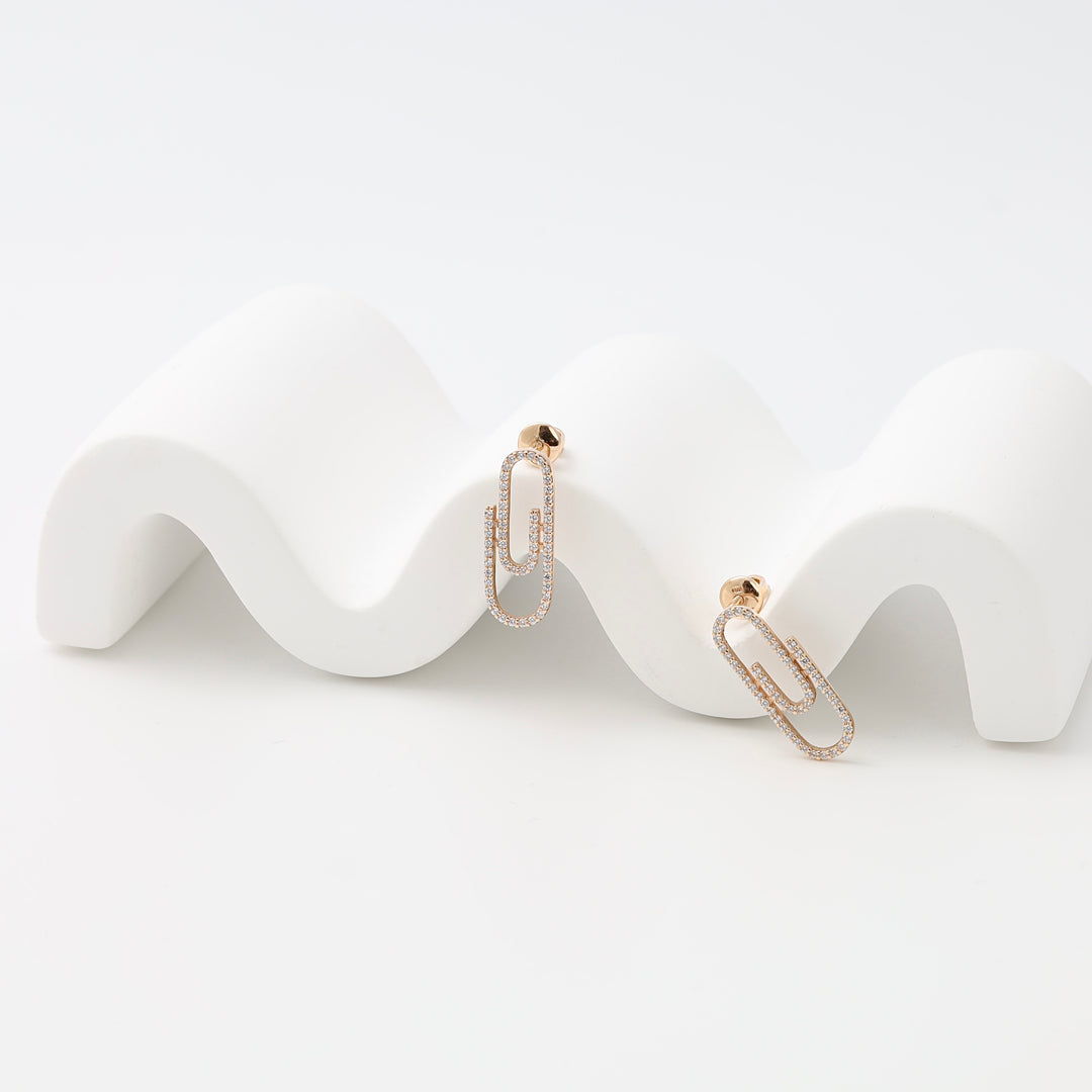 Pair of 14k gold paperclip drop earrings with small crystals on a white display, Ukrainian Jewelry, minimalist gold earrings.