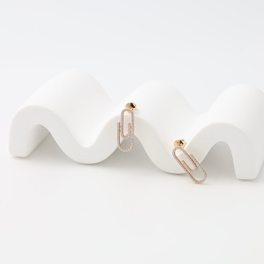 Pair of 14k gold paperclip drop earrings with small crystals on a white display, Ukrainian Jewelry, minimalist gold earrings.