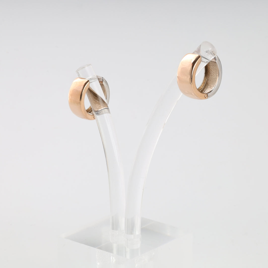 Pair of plain gold tone metal hoop earrings displayed on a clear acrylic stand.