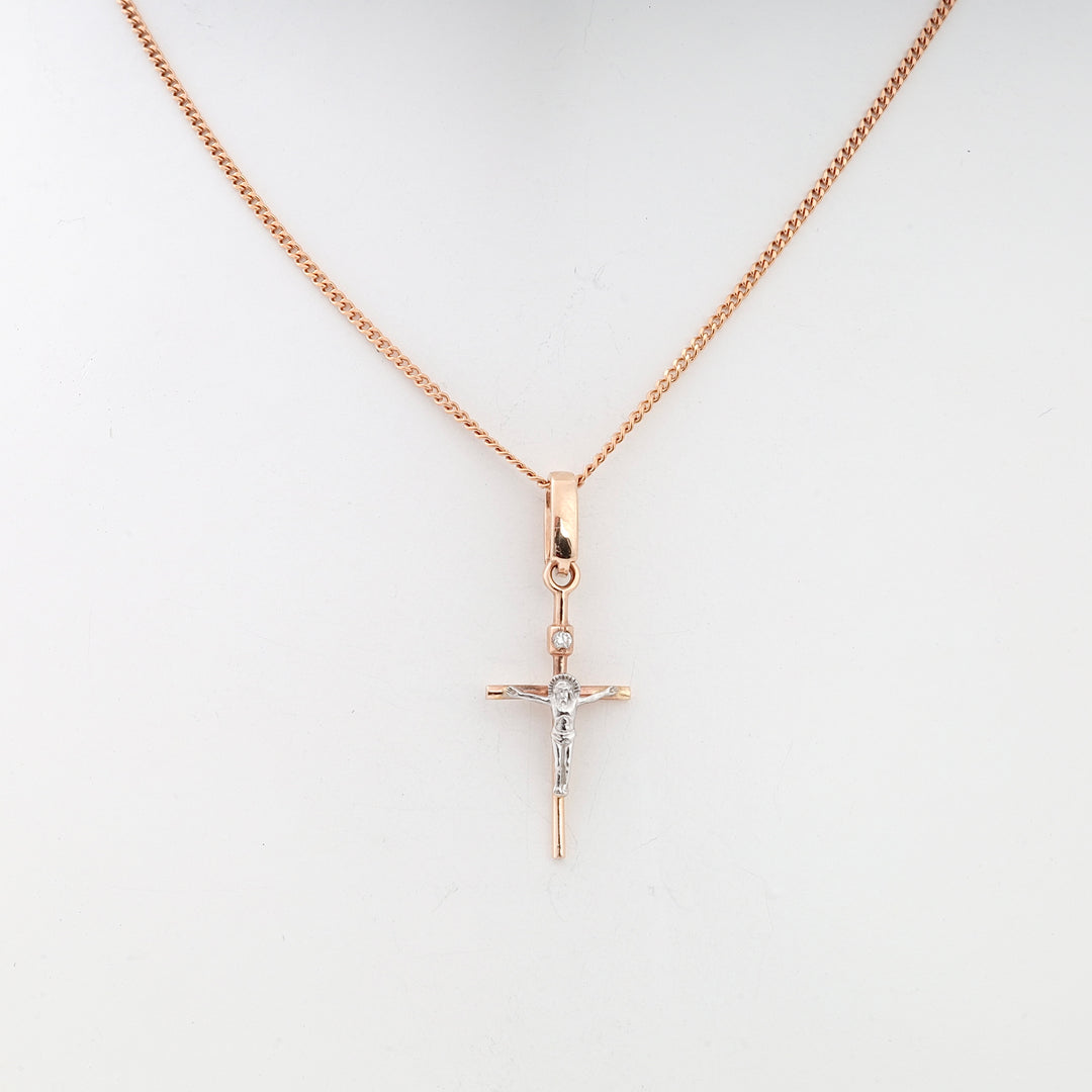 Rose gold chain necklace with a small crucifix pendant featuring a silver Jesus motif displayed on a white background.