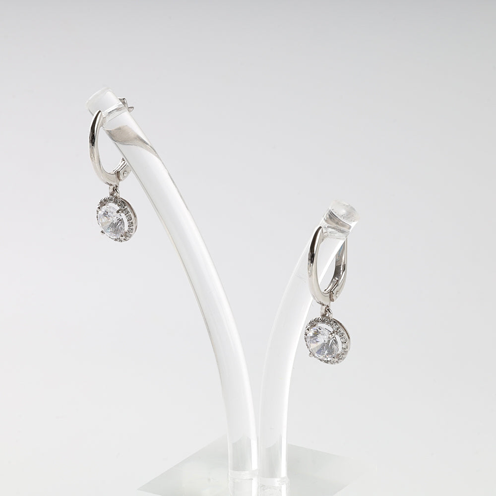 Silver hoop earrings with round clear gemstone dangles displayed on a white stand, cubic zirconia drop earrings.