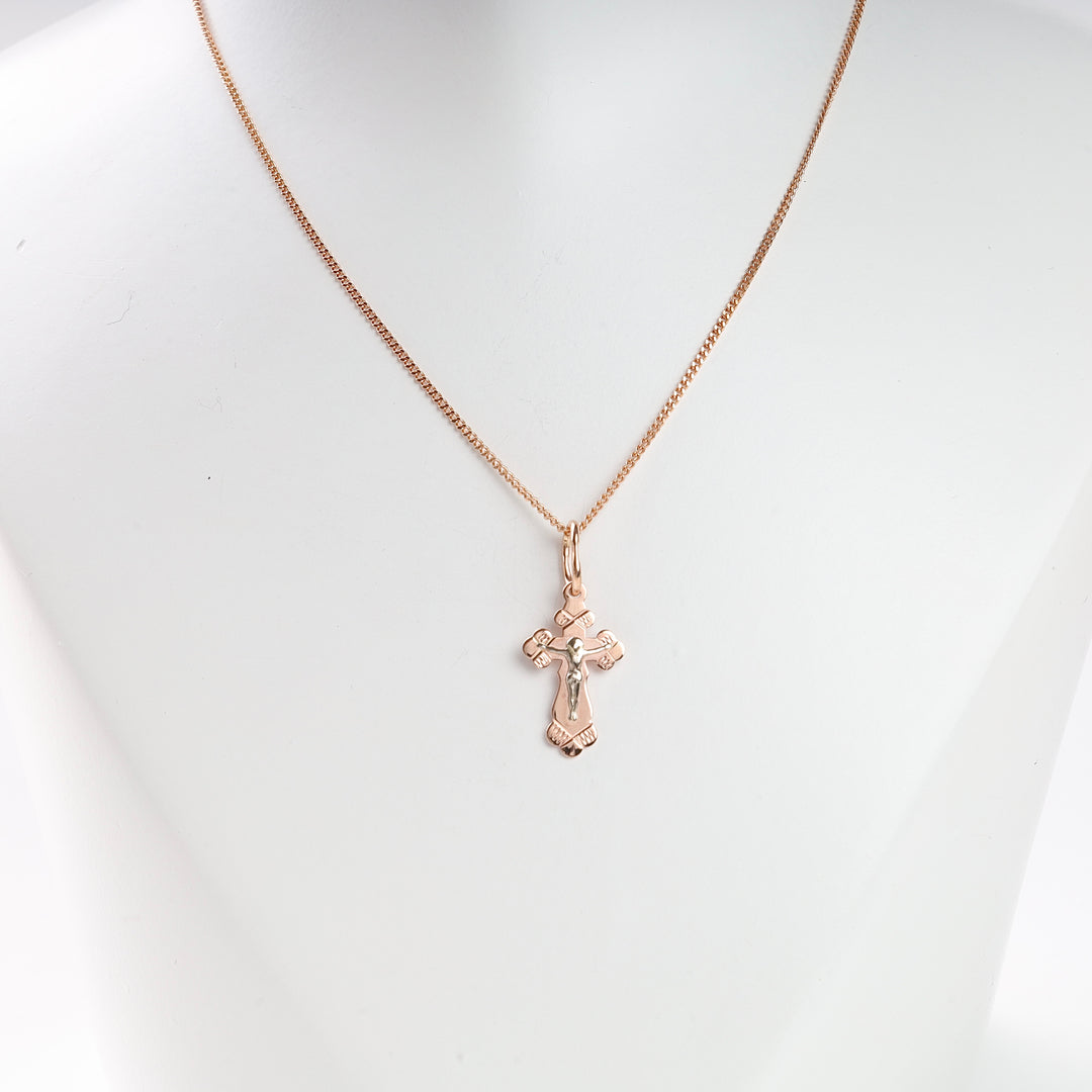 Gold cross pendant necklace featuring an engraved crucifix design, displayed on a white bust.