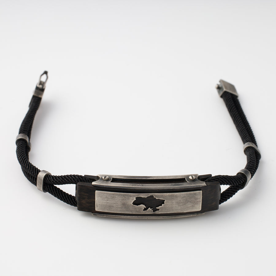 Black cord bracelet with a silver plate featuring a cutout map of Ukraine, shown on a white background.