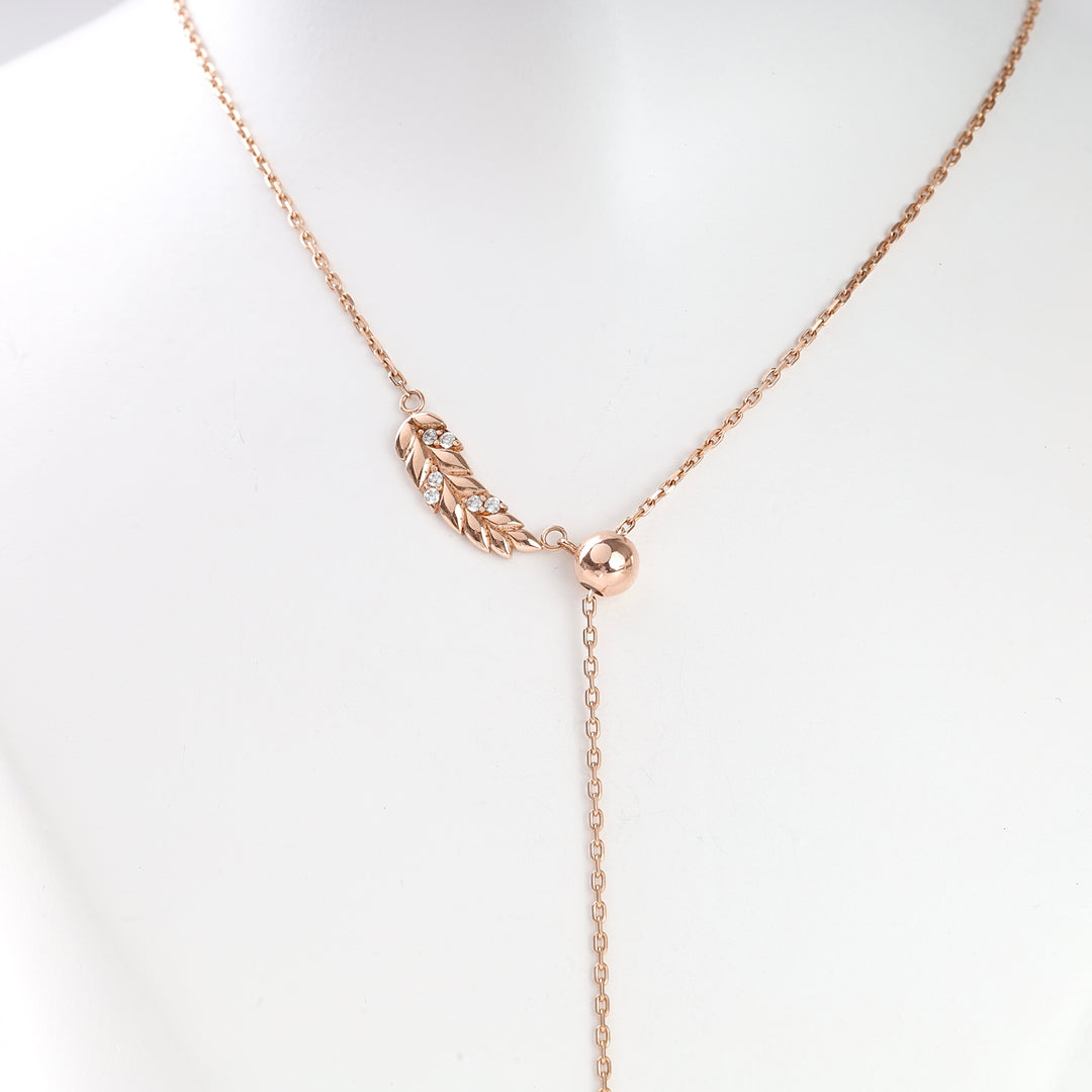 Rose gold necklace with a leaf motif and cubic zirconia stones on a fine chain, displayed on a white mannequin.