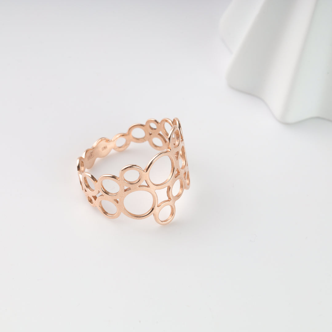 Openwork rose gold ring with oval and circle cutout design displayed on a white background for minimalist jewelry.