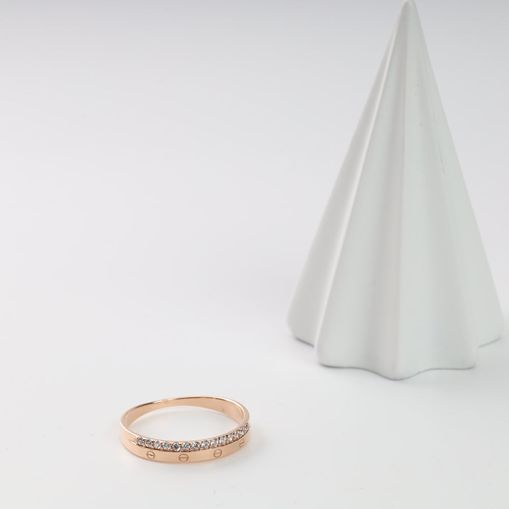 Rose gold ring with diamond accents displayed next to a white decorative cone.