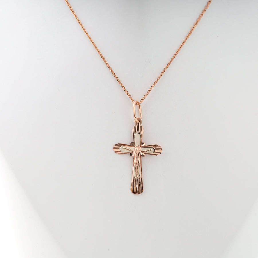 Rose gold crucifix pendant necklace with Jesus motif on a fine chain, displayed on a white background.