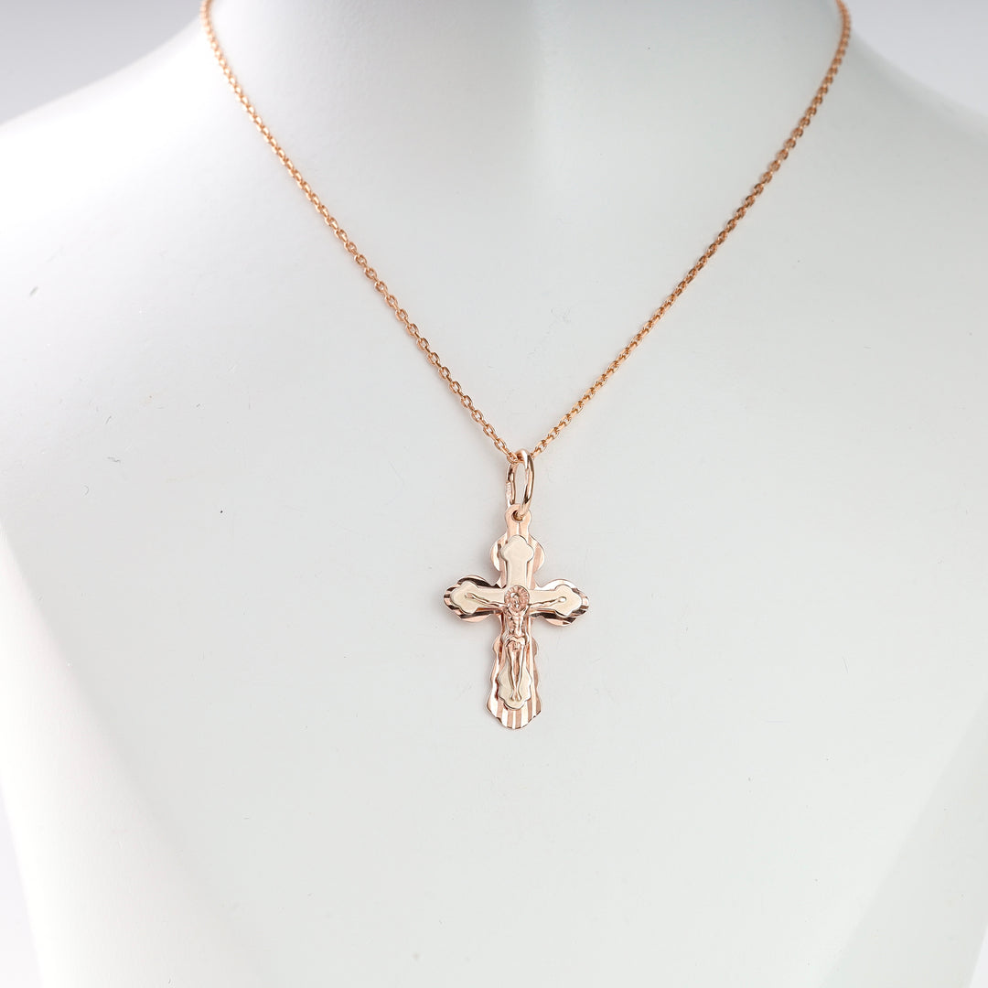 Rose gold crucifix pendant necklace with a detailed Jesus motif on a fine chain, displayed on a white bust.