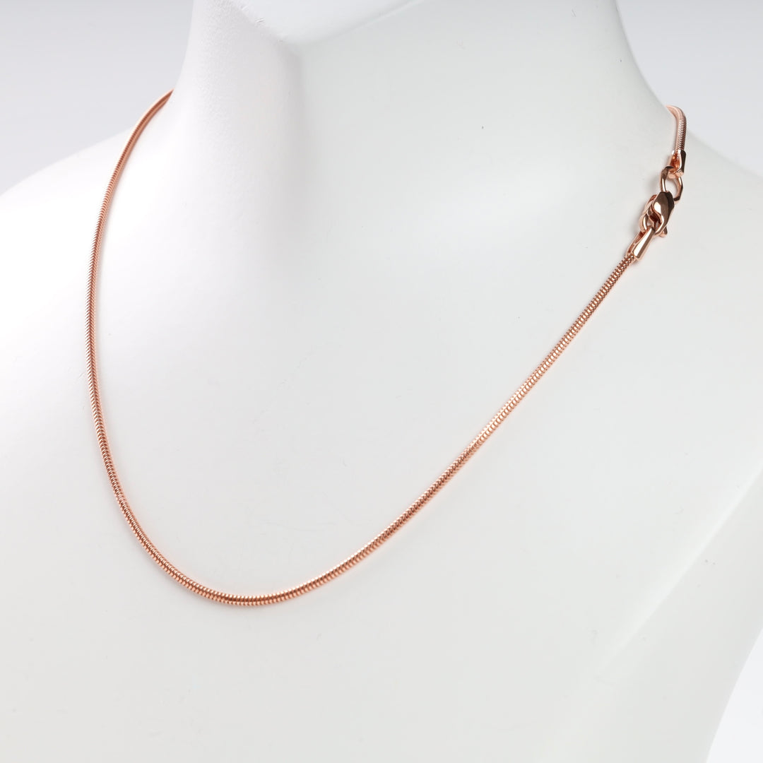Rose gold snake chain necklace on a white mannequin.