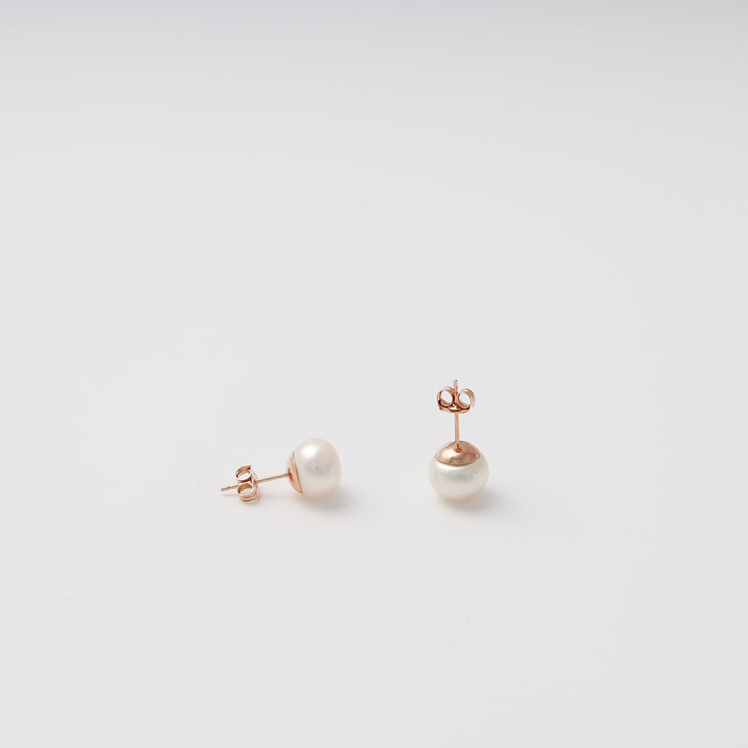 Pair of 14k gold pearl stud earrings on white background, classic Ukrainian Jewelry, simple gold studs, pearl earrings.