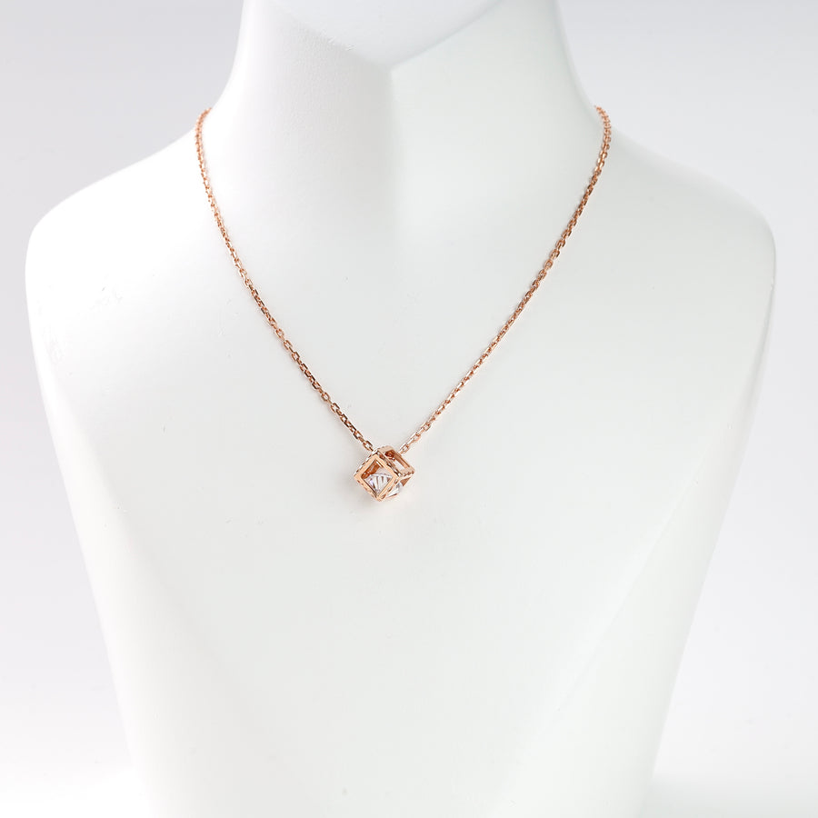 Rose gold chain necklace with a geometric square crystal pendant displayed on a white mannequin bust.