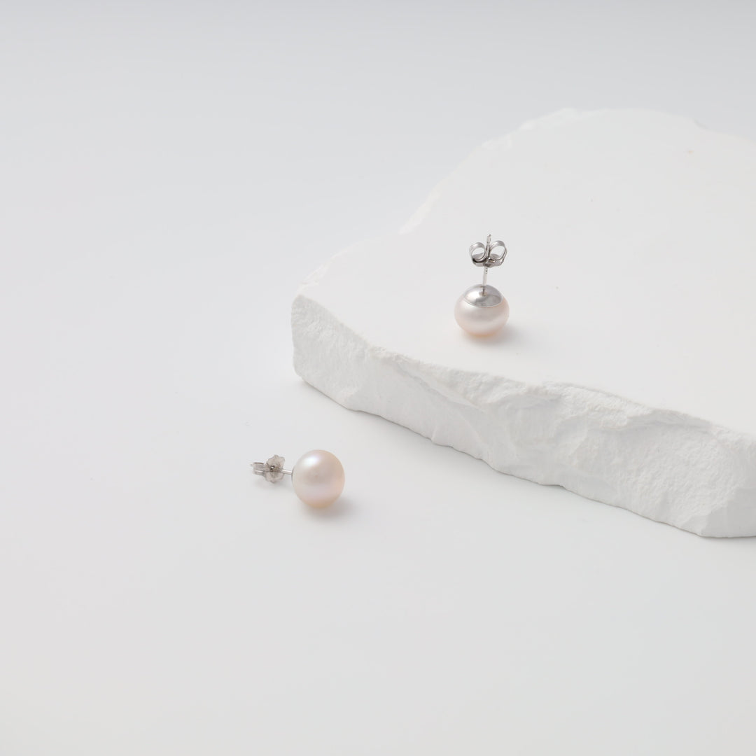 Sterling silver pearl stud earrings on white stone display, classic pearl earrings Ukrainian Jewelry for bridal and everyday wear.