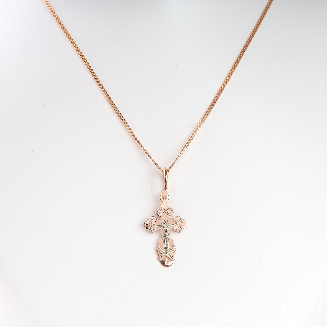 Rose gold cross pendant necklace with a Jesus motif displayed on a white background. Cross jewelry, religious necklace.