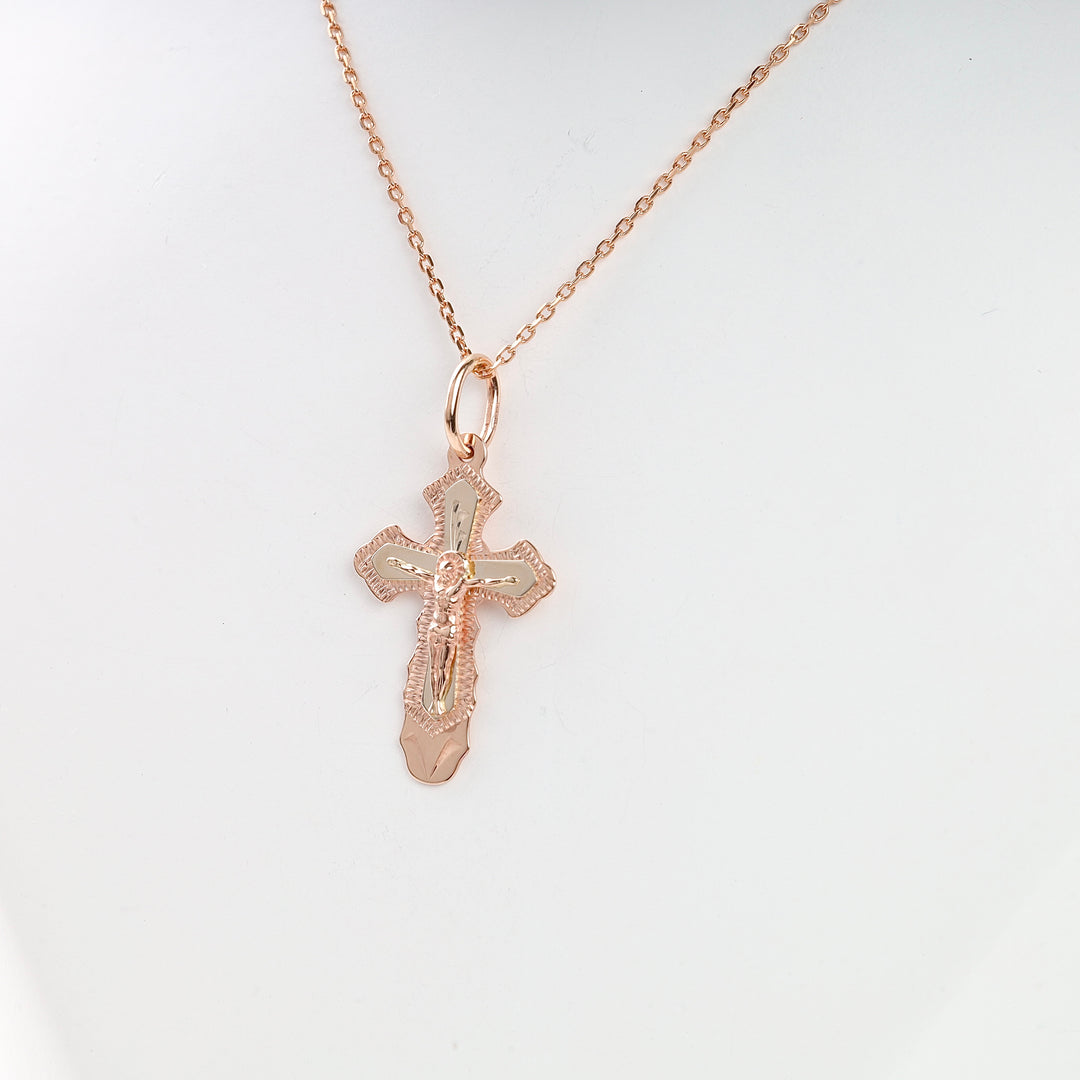 Rose gold crucifix pendant necklace with two-tone cross and figure of Jesus, shown on a fine chain.