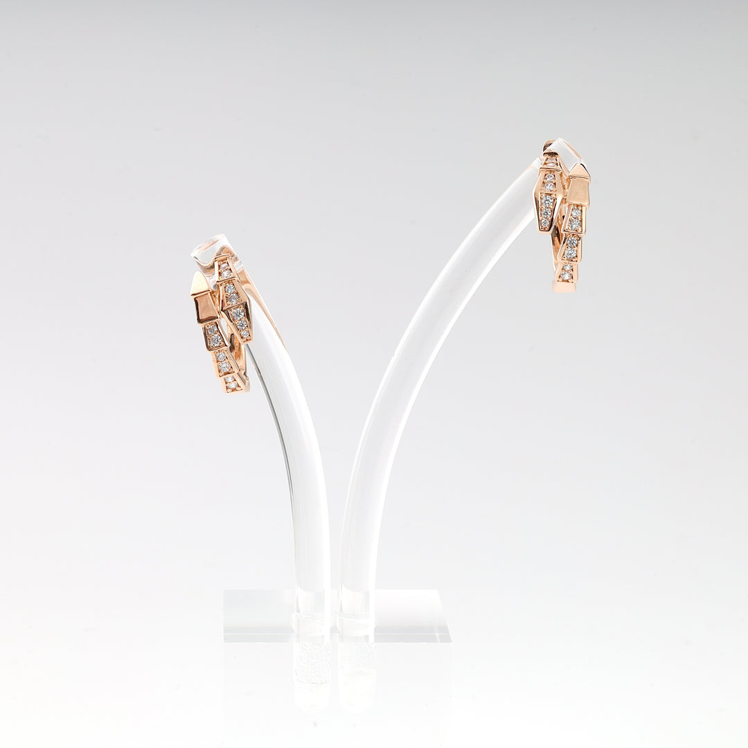 Pair of rose gold geometric hoop earrings with square clear stone accents displayed on a white stand.