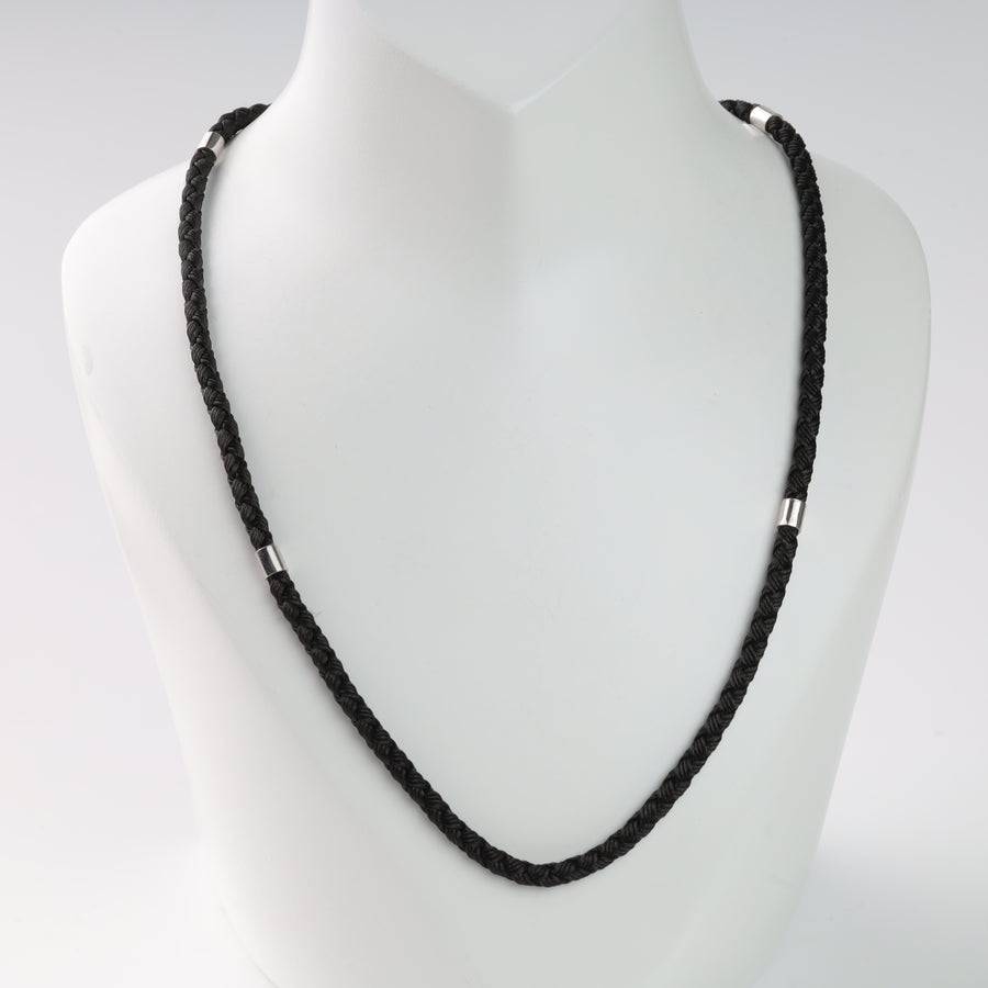 Black braided leather necklace with silver accents displayed on a white bust.