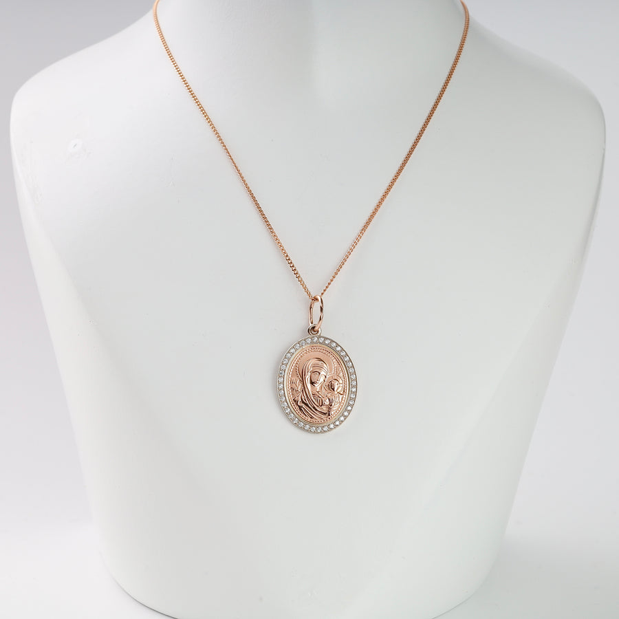 Rose gold necklace with round Virgin Mary medallion charm and clear crystal border on display bust. Religious pendant jewelry.