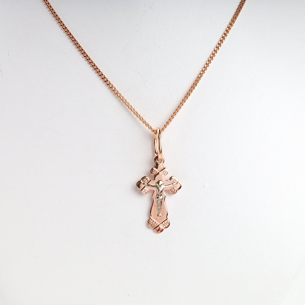 Rose gold crucifix pendant necklace with Jesus motif displayed on a simple chain.