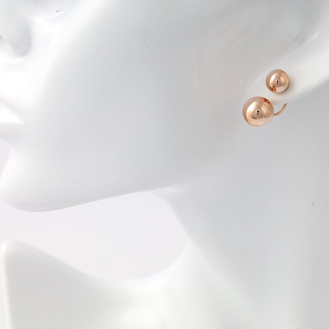 Rose gold earrings with double ball studs shown on ear mannequin, minimalist 14k gold jewelry, Ukrainian Jewelry for modern stud earring buyers.