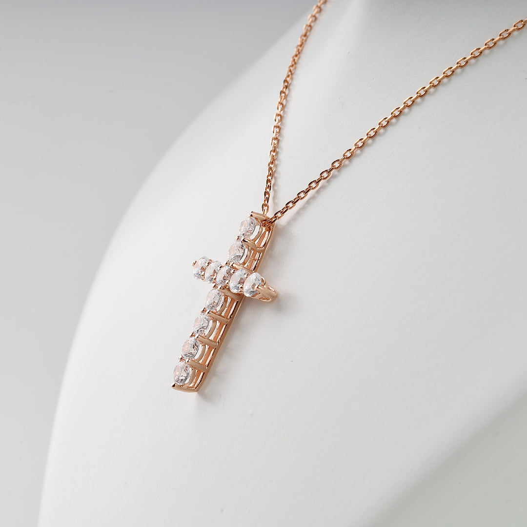 Rose gold chain necklace with a cross pendant featuring clear round gemstones, displayed on a white mannequin bust.