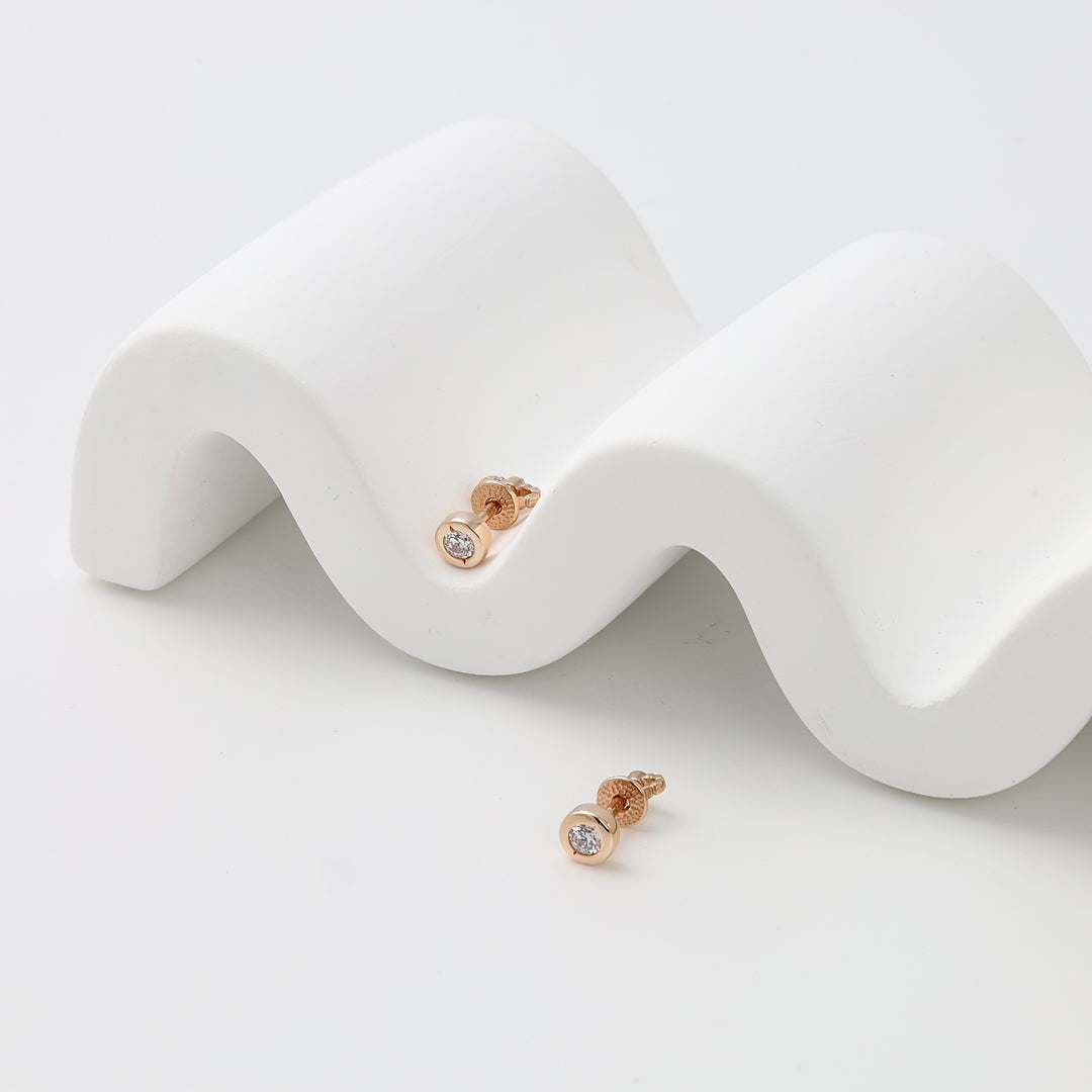 Pair of gold stud earrings with round clear stones on white display, minimalist Ukrainian Jewelry perfect as everyday gold earrings.