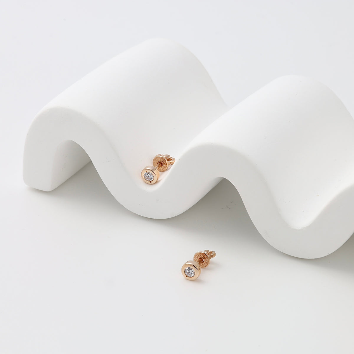 Pair of gold stud earrings with round clear stones on white display, minimalist Ukrainian Jewelry perfect as everyday gold earrings.