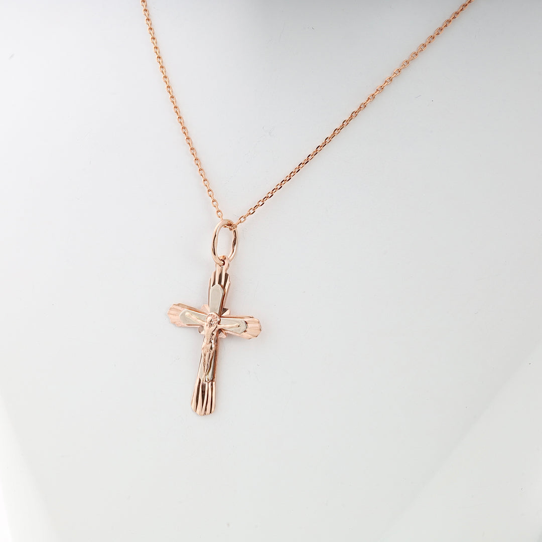 Rose gold crucifix necklace with a detailed Jesus motif on a fine chain, displayed against a white background.