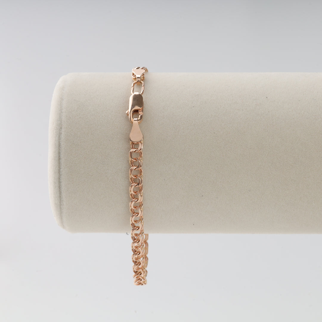 Rose gold chain bracelet with lobster clasp displayed on a light beige velvet jewelry holder.