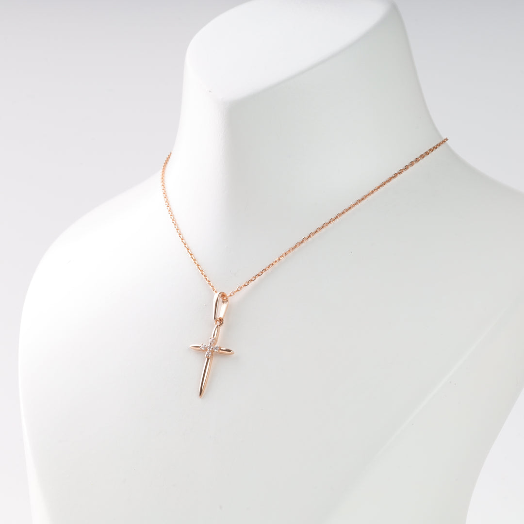 Gold cross pendant necklace with a small diamond center on a thin chain, shown on a white display bust.