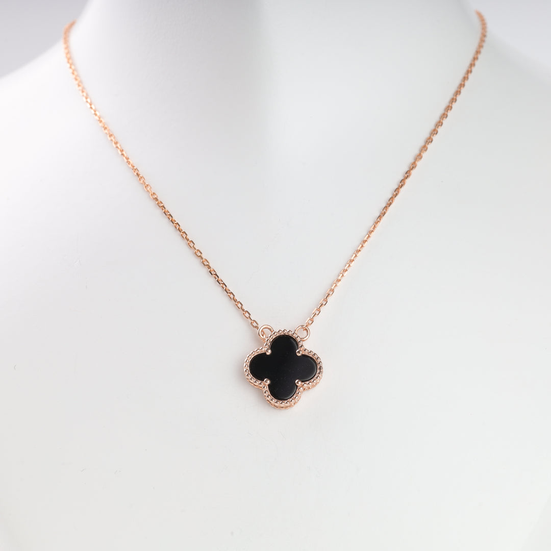 Rose gold chain necklace with a black clover-shaped pendant displayed on a white bust.