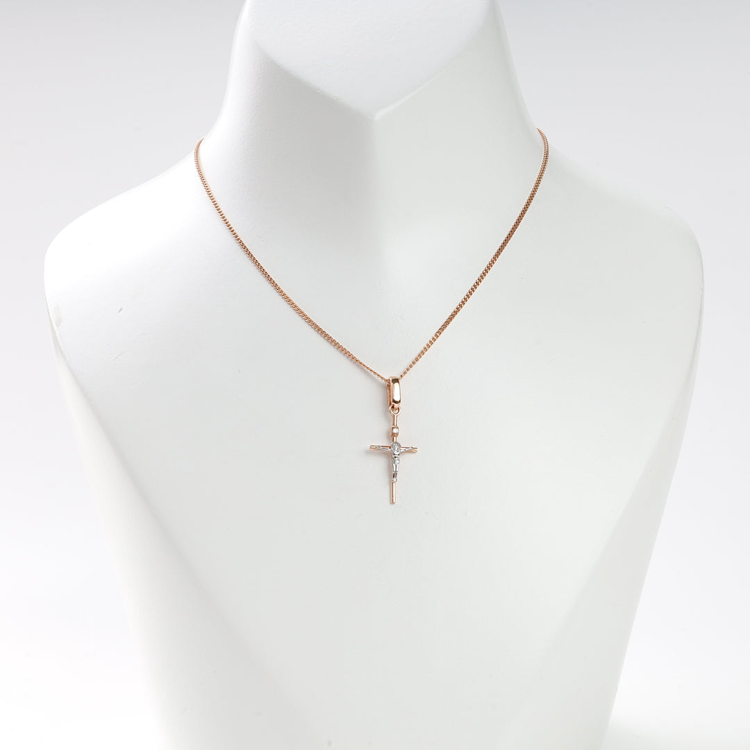 Rose gold chain necklace with a small crucifix pendant displayed on a white bust stand. Cross necklace, religious jewelry.