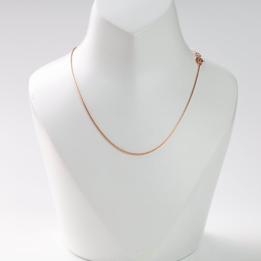 Rose gold snake chain necklace on a white jewelry bust.