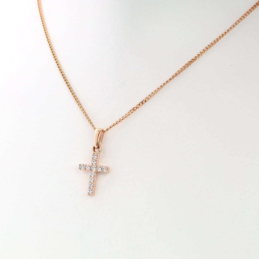 Rose gold chain necklace with a crystal cross pendant displayed on a white background, jewelry, religious necklace.