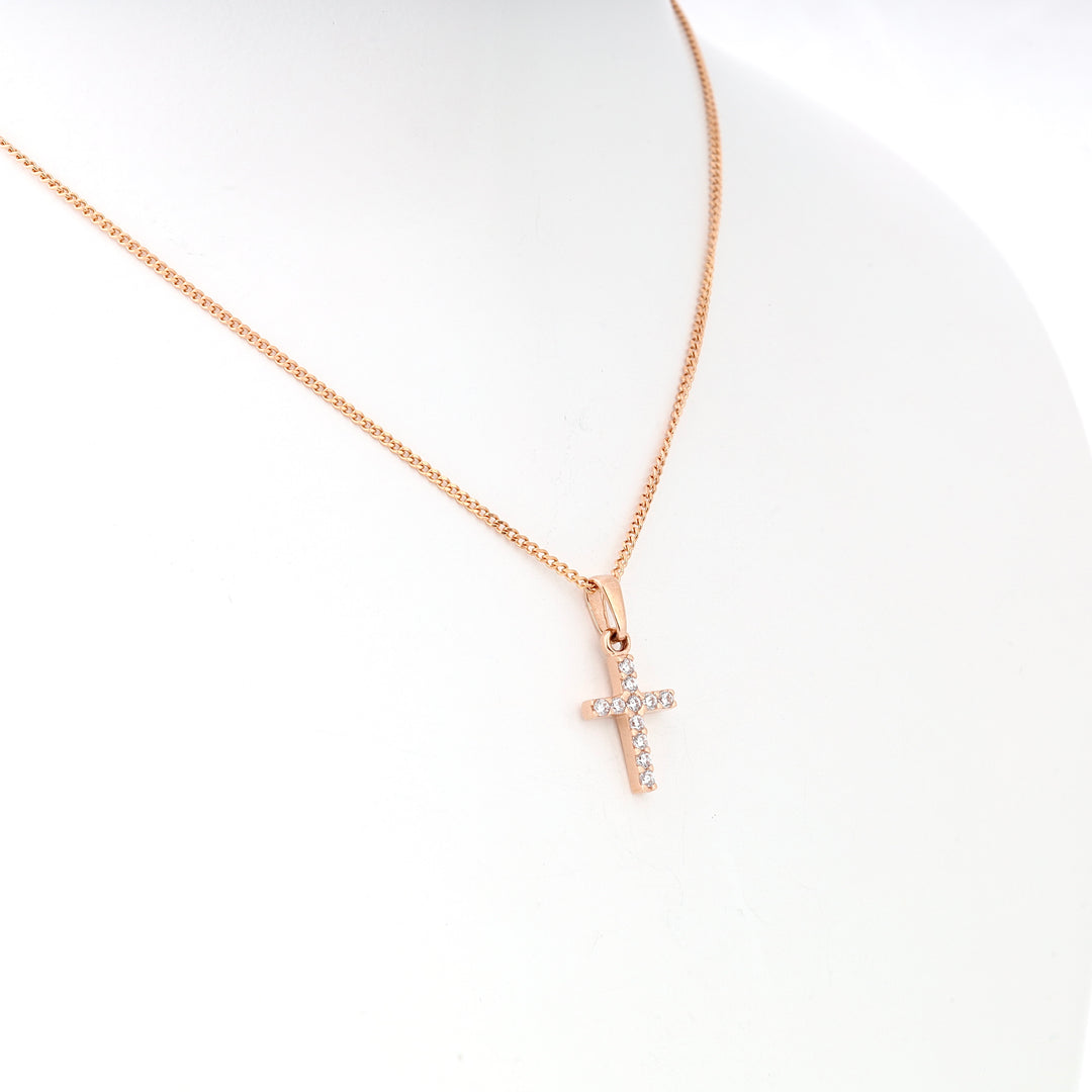 Rose gold chain necklace with a small cross pendant set with clear crystals, displayed on a white bust.