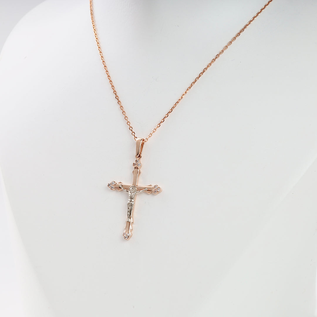 Rose gold crucifix necklace with small clear stones on a fine chain, displayed on a white bust.