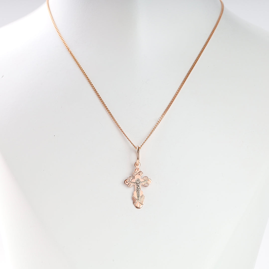 Gold crucifix pendant necklace displayed on a white bust, featuring a detailed cross design.