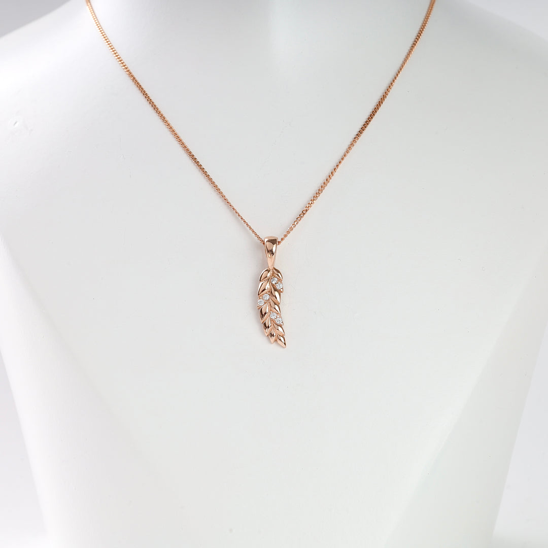 Rose gold necklace with a leaf pendant featuring small clear stones, displayed on a white bust.