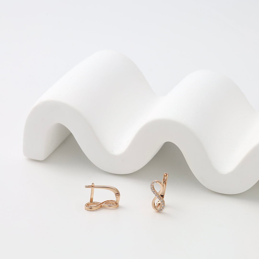 14k gold infinity drop earrings with small clear stones on white display, Ukrainian Jewelry, delicate gold dangle earrings gift.