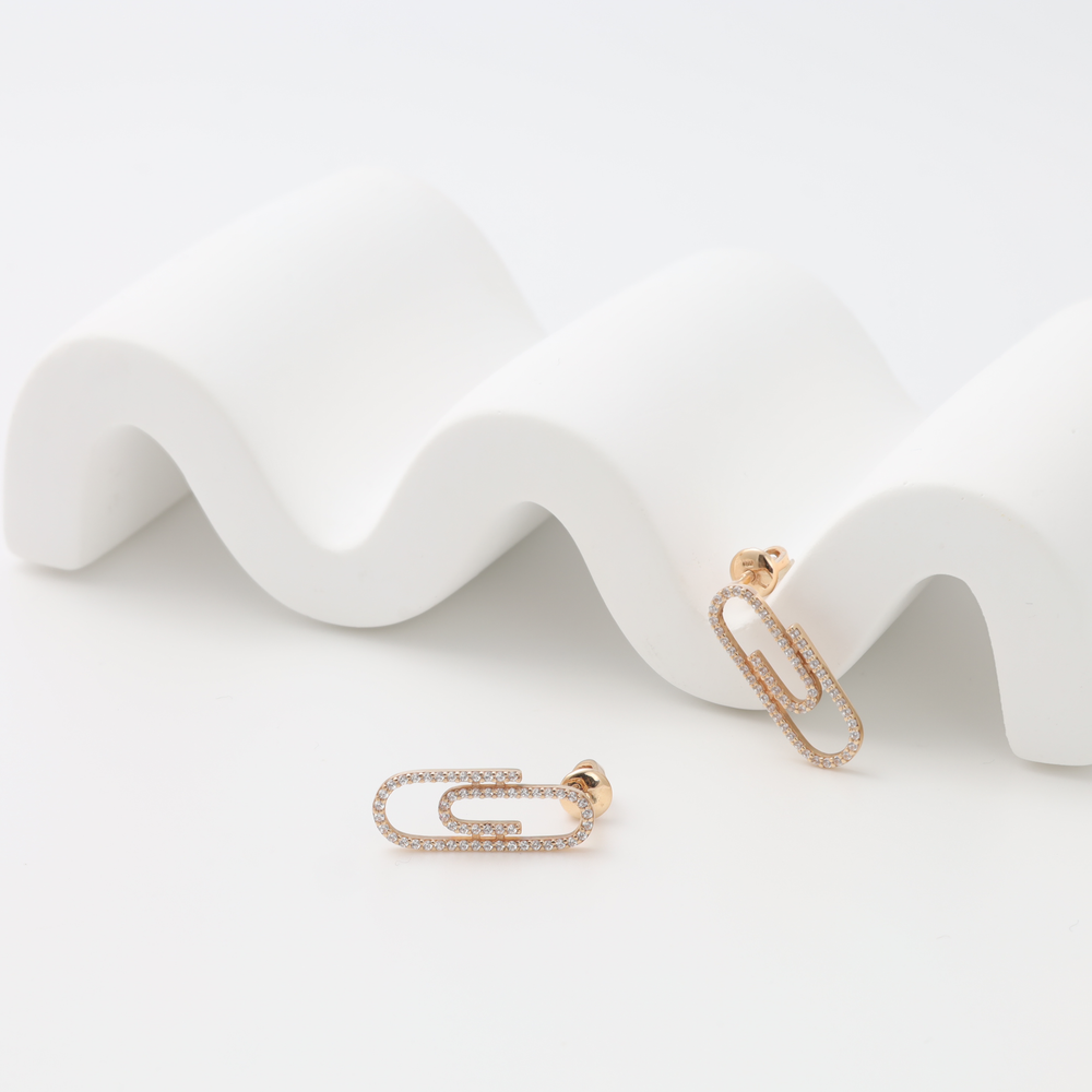 Pair of 14k gold paperclip stud earrings with small clear stones on white display, Ukrainian Jewelry, minimalist gold earrings.