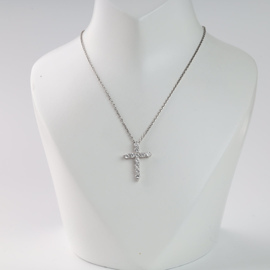 Silver chain necklace with a crystal cross pendant on a display stand.