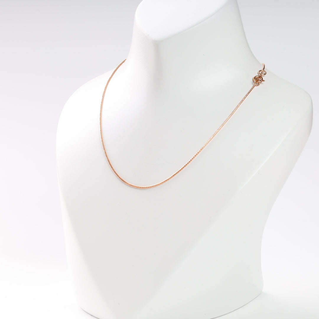 Gold chain necklace displayed on a white bust.