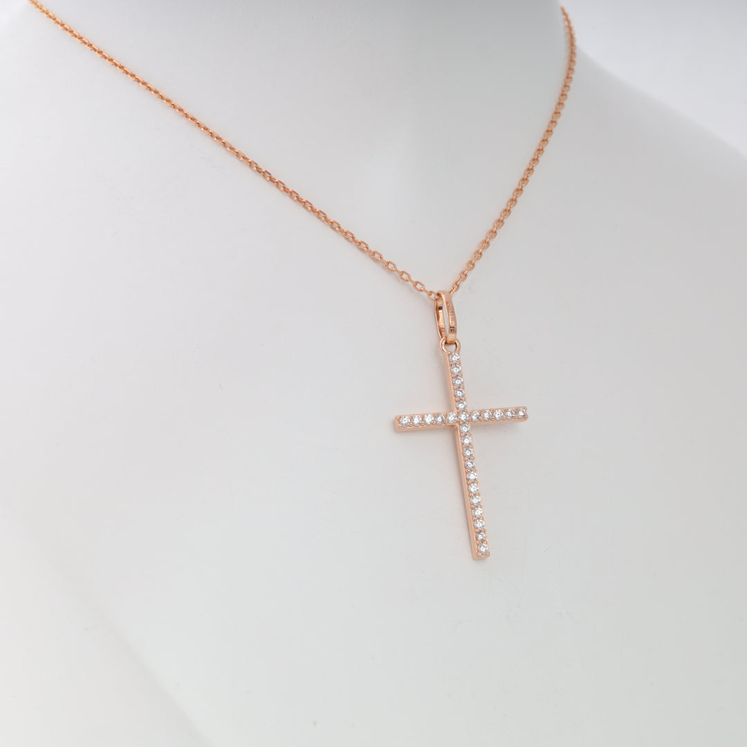Rose gold chain necklace with a crystal-studded cross pendant displayed on a white mannequin. Cross pendant necklace jewelry.