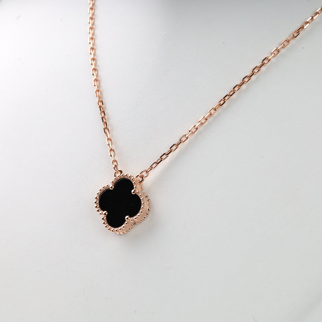 Rose gold necklace with a black clover-shaped pendant shown on a plain white background.