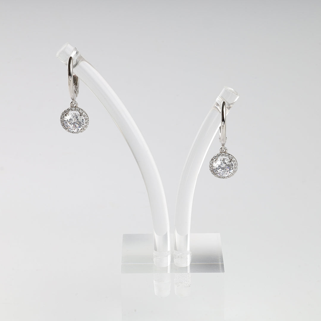 Pair of silver drop earrings with round clear crystals displayed on a white stand, halo setting jewelry, dangle earrings.