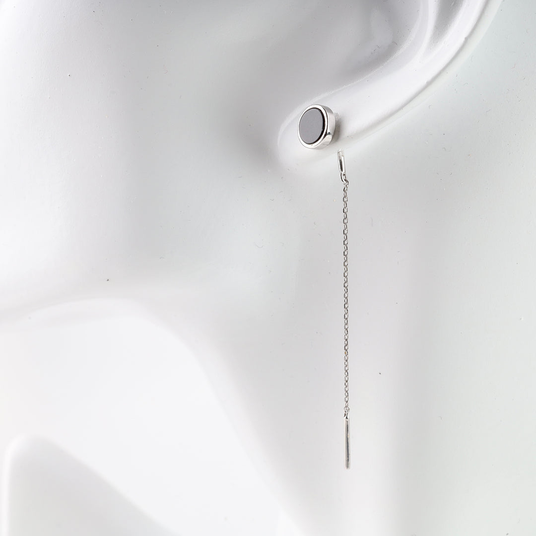 Single silver chain drop earring with a round black stud displayed on a white mannequin ear.