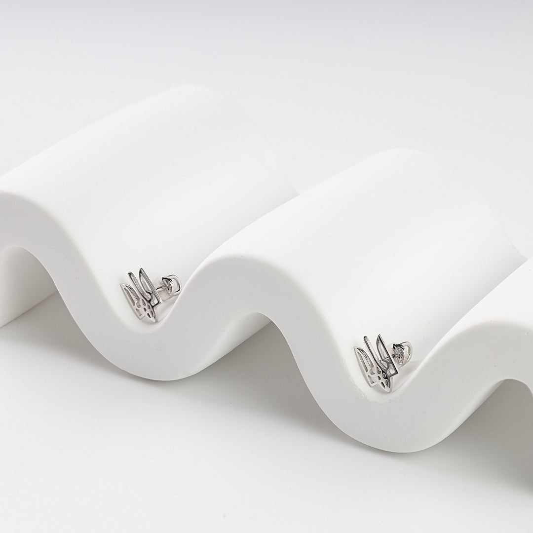 Pair of silver rabbit stud earrings with cut-out details displayed on a white wavy surface.