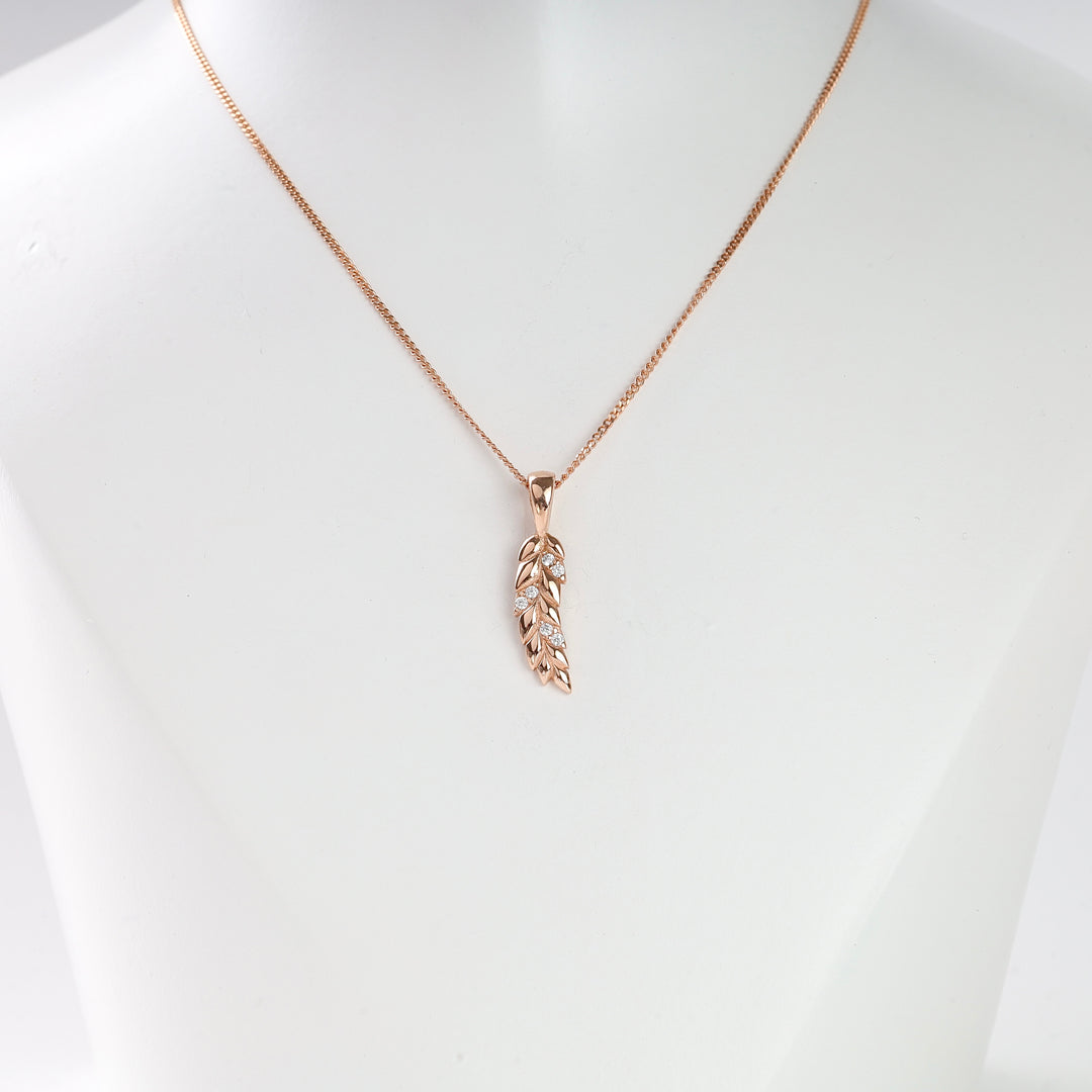 Rose gold chain necklace with a leaf-shaped pendant featuring clear stones, displayed on a white bust.